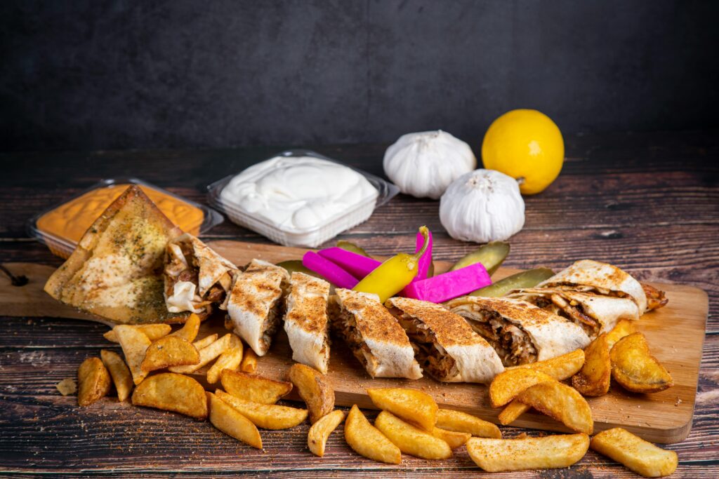 A mouthwatering Arabic shawarma platter with sides of fries, sauces, and fresh vegetables.
