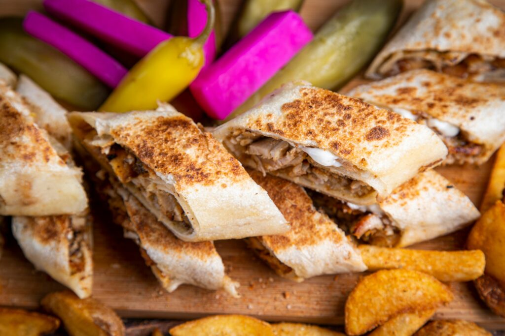 Delicious Middle Eastern shawarma wraps served with pickles and fries, perfect for a hearty meal.